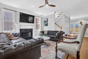 Ein Wohnzimmer mit Kamin, Ledersofas, einem Couchtisch und einer Treppe.