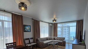 Una sala de estar moderna con un sofá modular, una mesa de comedor, sillas y un televisor.