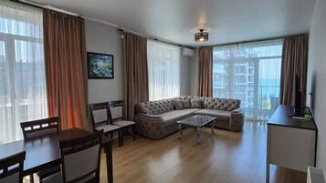 Una sala de estar moderna con un sofá modular, una mesa de comedor, sillas y un televisor.