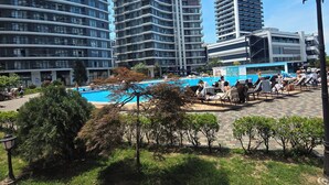 Un hotel moderno con piscina, rodeado de vegetación y edificios altos.