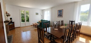 Un comedor con mesa y sillas de madera, un sofá verde y vistas al exterior.