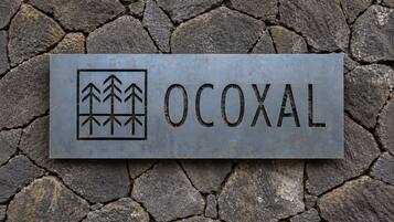 Placa de metal com a palavra 'OCOXAL' e um símbolo de árvores.