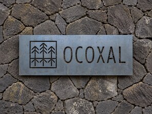 A metal sign with the word 'OCOXAL' and a symbol of trees.