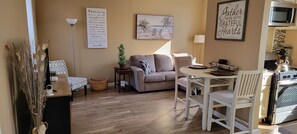 A cozy living area with a sofa, a dining table, and a kitchen area with a stove. - Cozy 1-bedroom Queen City Urban Escape (Cincinnati)