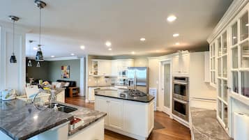 Una cocina moderna con armarios blancos, electrodomésticos de acero inoxidable y encimera de mármol.
