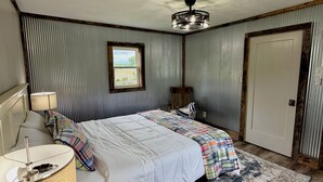 A bedroom with a bed, a lamp, a rug, a door, and a window. - Cumberland Blue- Cozy, Rustic Cottage Near Lake Cumberland (Jamestown)
