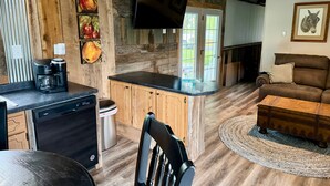A kitchen with wooden cabinets, a coffee maker, and a TV. - Cumberland Blue- Cozy, Rustic Cottage Near Lake Cumberland (Jamestown)