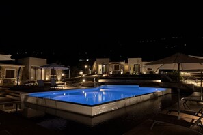 Une piscine entourée d’une terrasse, de chaises longues et de parasols.