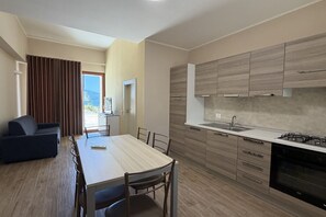 Une cuisine moderne avec des meubles en bois, une table à manger avec des chaises et une vue sur l’extérieur.