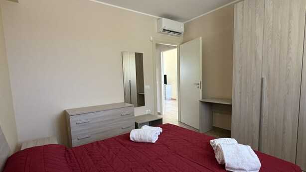 A bedroom with a bed, a dresser, a mirror, an air conditioning unit, and a wardrobe. - Sea-view apartment with a pool (Telegrafo)