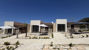 A modern building with a stone patio, outdoor seating, and a clear blue sky. - Sea-view apartment with a pool (Telegrafo)