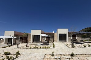 Um edifício moderno com pátio de pedra, área de estar externa e céu azul límpido.