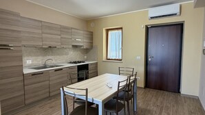 A modern kitchen with a dining table, cabinets, and a window. - Sea-view apartment with a pool (Telegrafo)