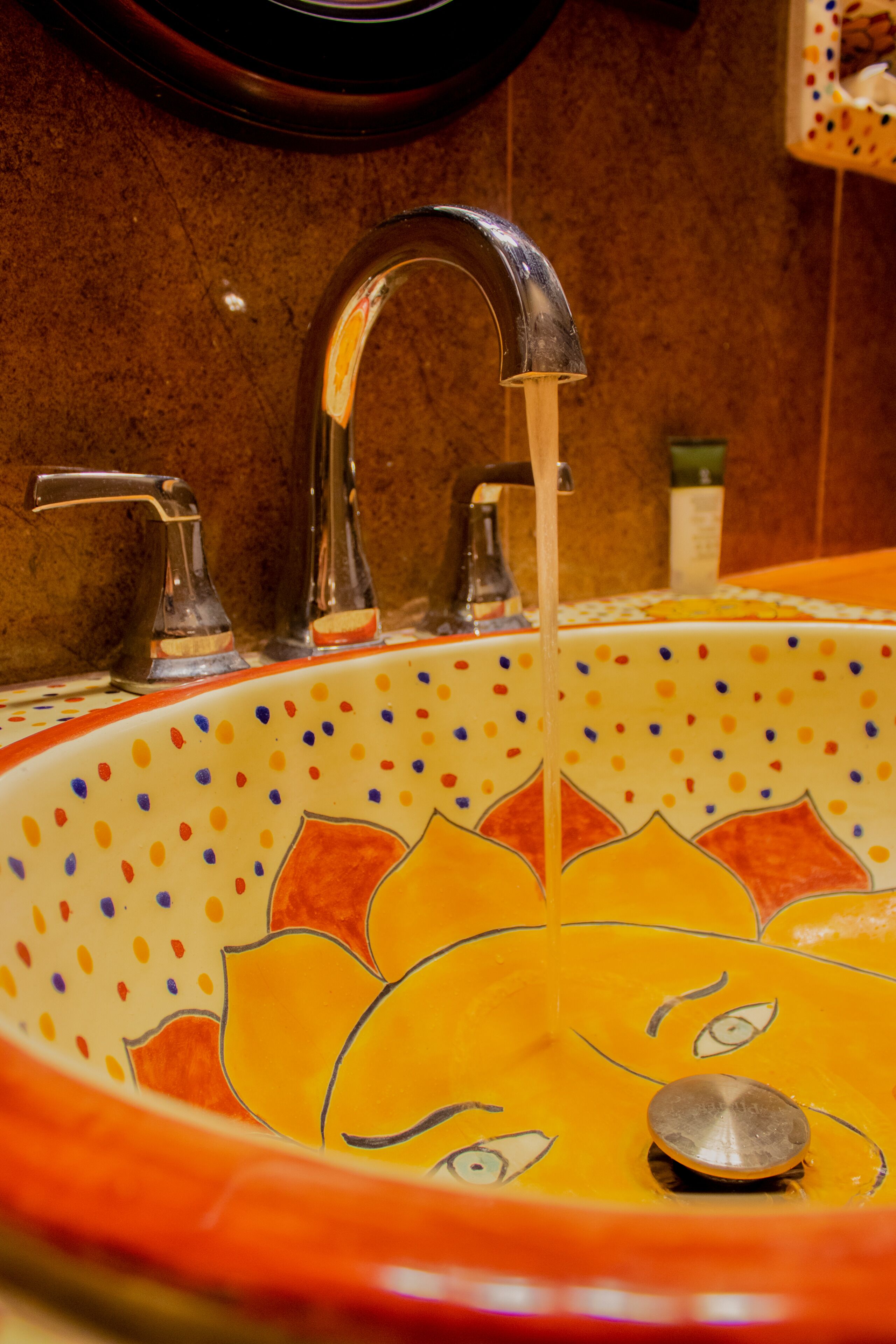A bathroom sink with a decorative design and multiple faucets.