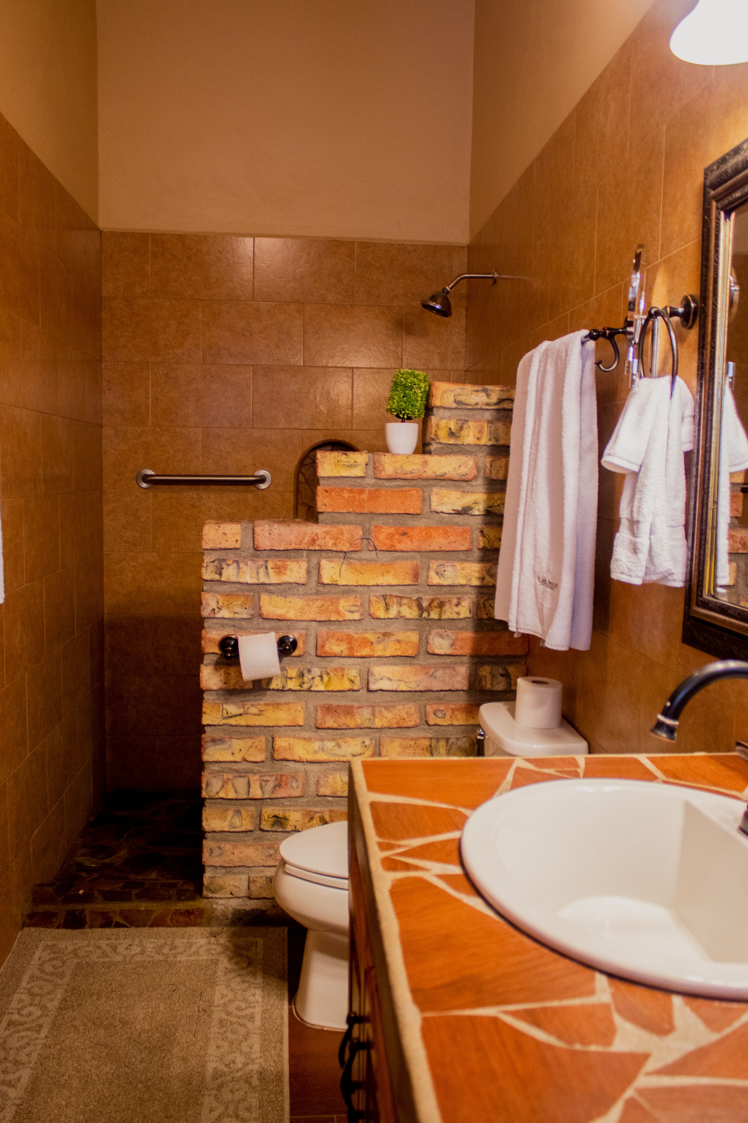 A bathroom with a brick wall, a white sink, a mirror, and a towel rack.