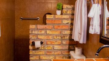A bathroom with a brick wall, a white sink, a mirror, and a towel rack.