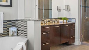 A modern bathroom with a bathtub, a vanity with a mirror, and a shower area.