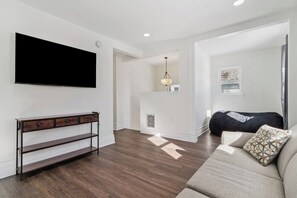 Ein modernes Wohnzimmer mit Flachbildfernseher, einer Couch, einem Konsolentisch und einem Kamin.