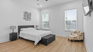 Ein Schlafzimmer mit einem Bett, Nachttischen, einer Bank und einem Sessel.