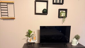 Ein schwarzes Unterhaltungsmöbel mit Flachbildfernseher, einer kleinen Pflanze und einem gerahmten Spiegel an der Wand.