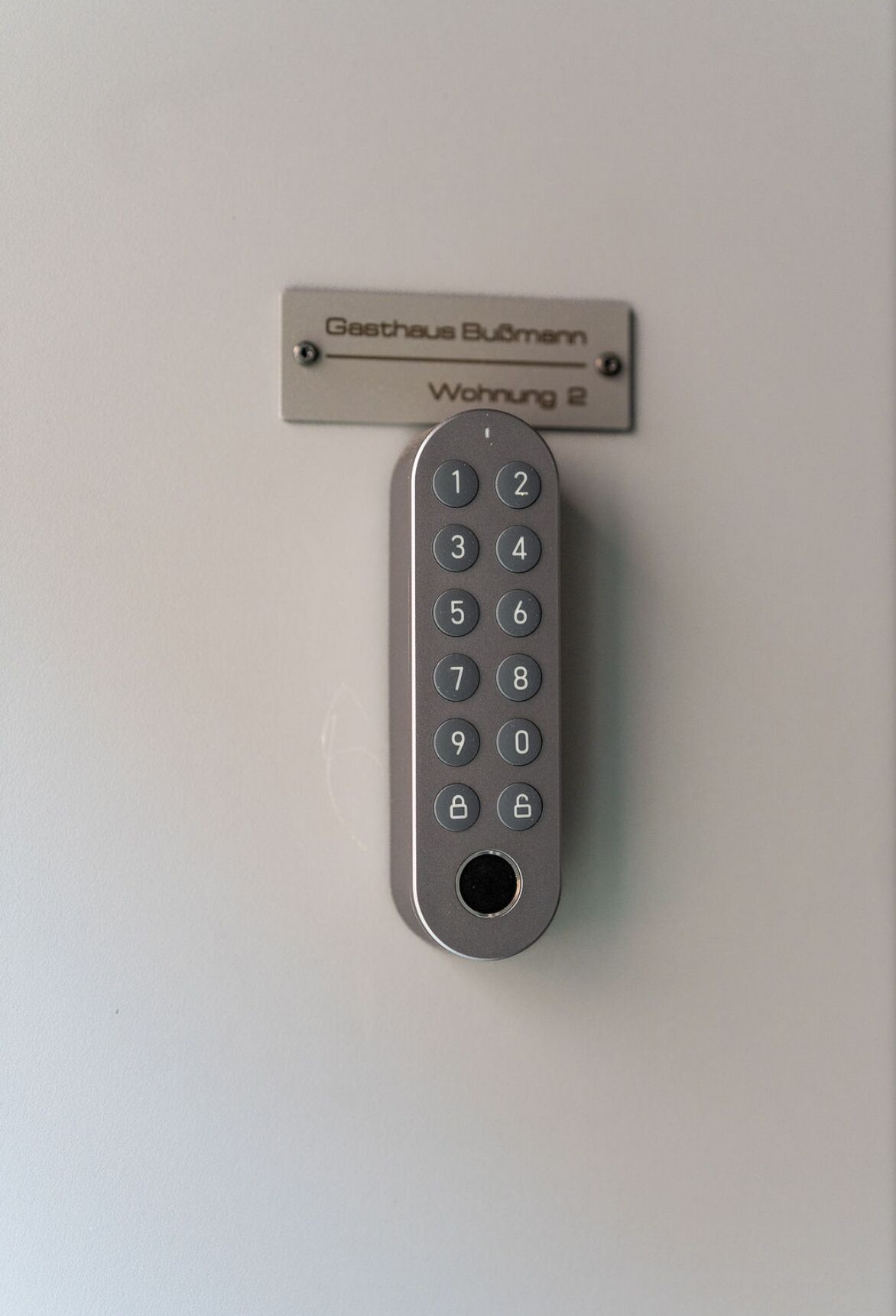 Un teclado numérico con un símbolo de candado, fijado a una pared con un cartel encima.