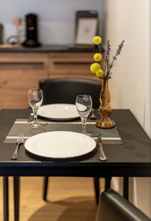 Ein Esstisch ist gedeckt mit Tellern, Besteck und einer Blumenvase.