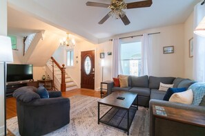 Ein Wohnzimmer mit Fernseher, Sofa, Couchtisch und einer Treppe.