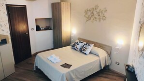 A bedroom with a bed, bedside lamps, a nightstand, a wardrobe, and a wall-mounted light fixture.