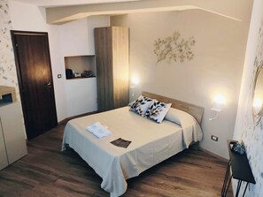 A bedroom with a bed, bedside lamps, a nightstand, a wardrobe, and a wall-mounted light fixture.