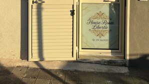 A building entrance with a closed shutter door, a window with a decorative glass panel, and an air conditioning unit mounted above.