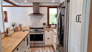 A modern kitchen with a central island, built-in oven, and stainless steel appliances. - Charming waterfront Salt Spring Island B&B (Saltspring Island)
