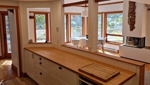 A kitchen with wooden countertops, white cabinets, and large windows. - Charming waterfront Salt Spring Island B&B (Saltspring Island)