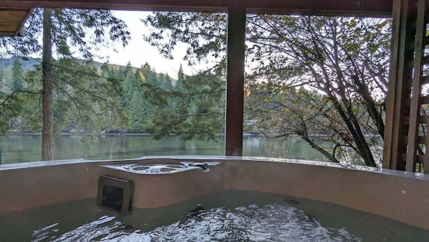 A hot tub with a view of a forested lake. - Charming waterfront Salt Spring Island B&B (Saltspring Island)