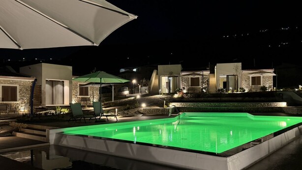 Ein Swimmingpool mit grüner Beleuchtung, Sitzgelegenheiten im Freien und moderner Architektur.