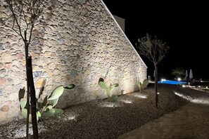 Ein Gebäude aus Stein mit einem geneigten Dach, einem Schwimmbad und einigen Bäumen.