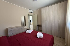 Ein Schlafzimmer mit Bett, Schminktisch, Spiegel, Kleiderschrank und Klimaanlage.