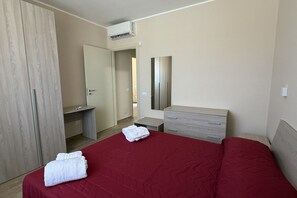 Ein Hotelzimmer mit Bett, Schminktisch, Spiegel, Kleiderschrank und Klimaanlage.