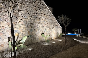 A stone building with a sloped roof, a pool, and a few trees.