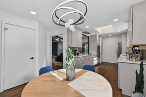 A modern kitchen with white cabinets, a stainless steel refrigerator, and a built-in oven. - Timeless Charm w/ Pool, Backyard, Patio (5BD/2BA) (Dallas)