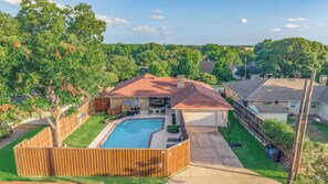 A residential property with a swimming pool, fenced yard, and a detached garage. - Timeless Charm w/ Pool, Backyard, Patio (5BD/2BA) (Dallas)