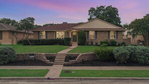 A two-story house with a front entrance, a driveway, and a well-maintained lawn. - Timeless Charm w/ Pool, Backyard, Patio (5BD/2BA) (Dallas)