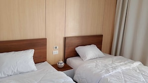 A hotel room with two beds, wooden headboards, white bedding, a small decorative vase, and a power outlet on the wall. - Protels Royal Bay Resort & Spa (Hurghada)