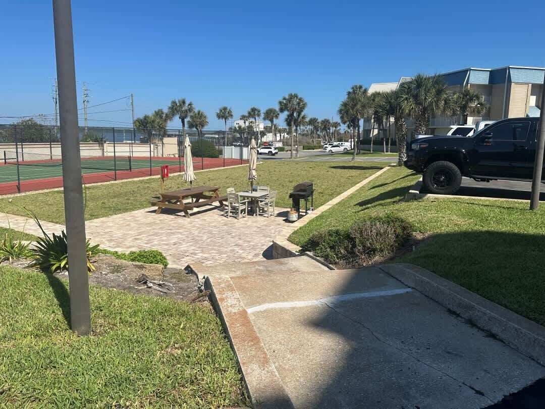 A sports field with a picnic area, a bench, and a trash bin.