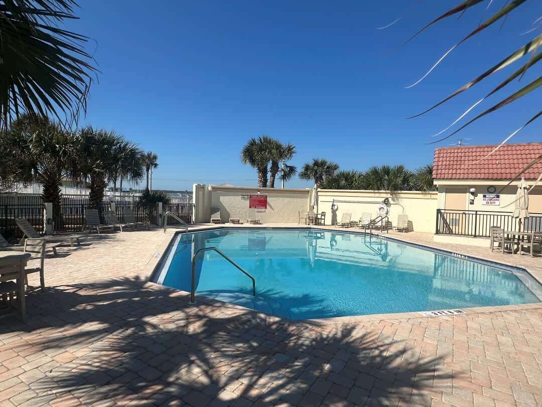 Una piscina amb terrassa enrajolada, palmeres i gandules.