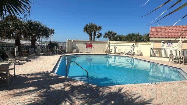 A swimming pool with a tiled deck, palm trees, and lounge chairs. - Ocean Front Beach Condo - Windjammer 410 (St. Augustine)