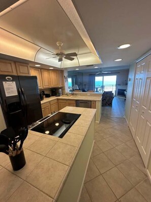 A modern kitchen with a central island, built-in appliances, and a view to the balcony. - Ocean Front Beach Condo - Windjammer 410 (St. Augustine)