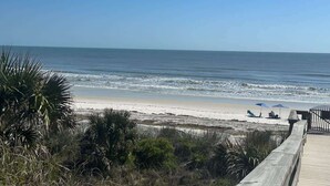 A beach view with a wooden boardwalk, beach umbrellas, and chairs. - Ocean Front Beach Condo - Windjammer 410 (St. Augustine)