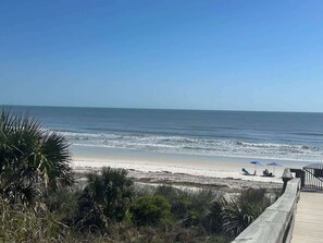 A beach view with a wooden boardwalk, beach umbrellas, and chairs. - Ocean Front Beach Condo - Windjammer 410 (St. Augustine)