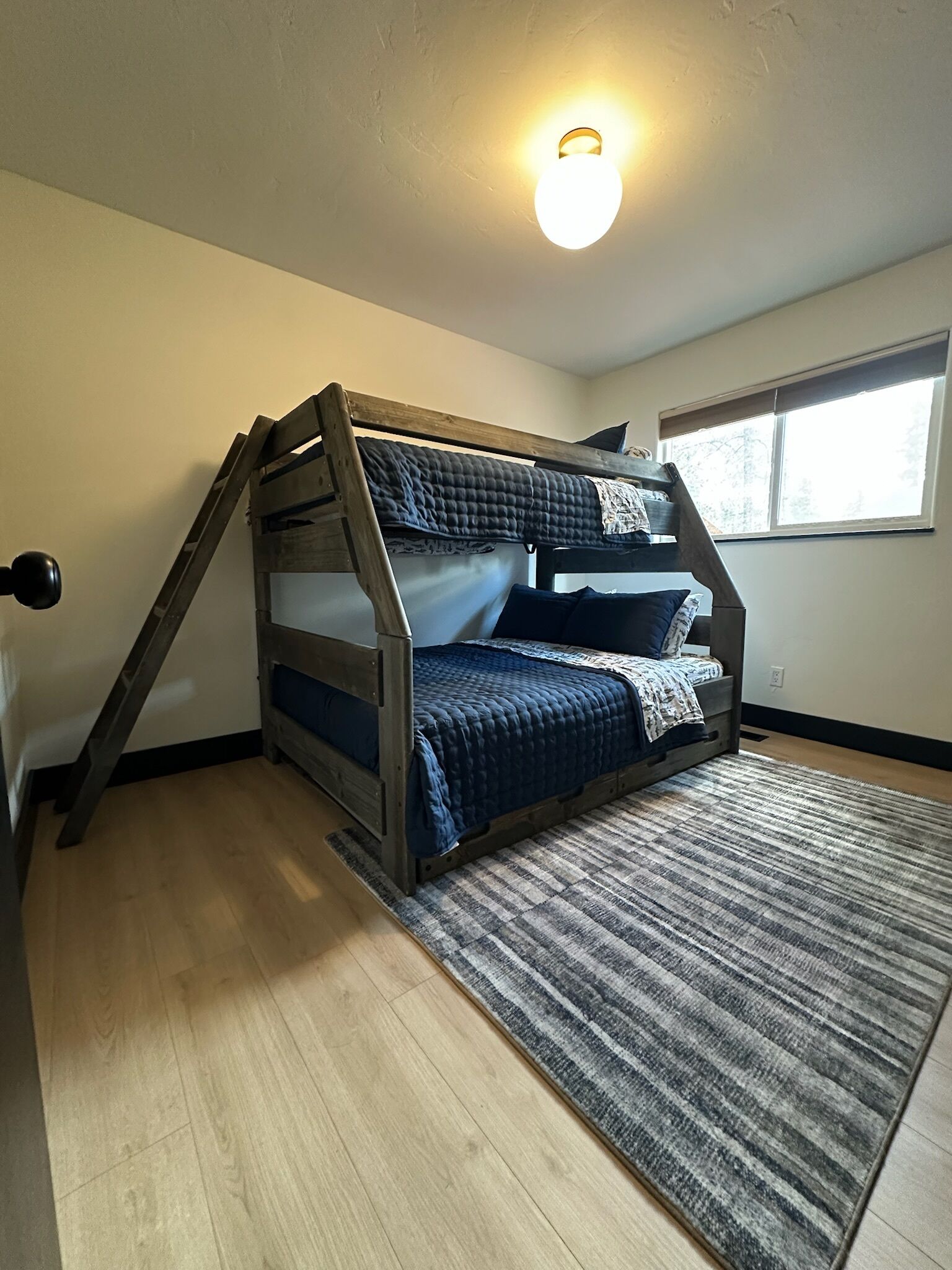 A bunk bed with a sloped ceiling and a light fixture above it.