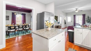 A modern kitchen with white cabinets, a granite countertop, and a stainless steel refrigerator. - Backyard Hangout Firepit, Giant Connect 4 & BBQ (Raleigh)